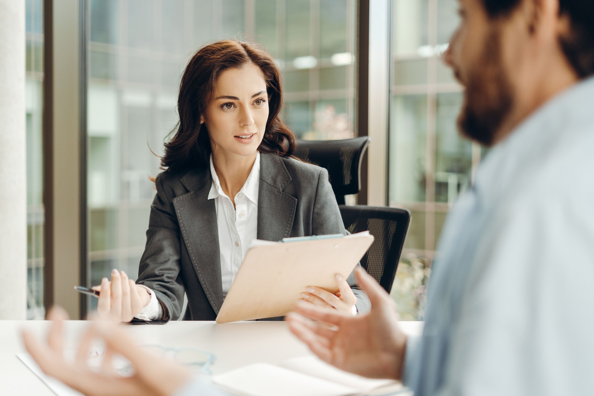 Businesswoman holding clipboard and talking to colleagues during meeting